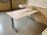 Angled view showing the white wood laminate desk surface and gray metal legs with the removable white storage unit placed on top.