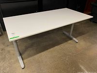 Full view of Ikea Galant desk showing white laminate top and metal T-shaped legs on concrete floor.