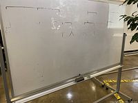 Full view of the two-sided whiteboard with writing visible on one side and metal frame with caster wheels.