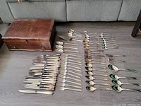 Full layout of all flatware and storage chest. Pieces neatly arranged showing variety and quantity.
