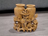 Front view of Chinese carved soapstone brush pot showing two vase-like containers and detailed floral carvings on the front with leaves and flowers.