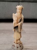 Front view of the carved soapstone man holding a fan, showing detailed facial features and folds in robes.