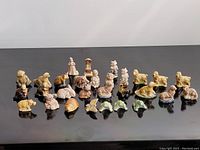 Full view of all 29 Wade ceramic figurines arranged on a reflective black surface, showing a variety of animals and a few human figures