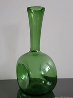 Front view of the green glass vase showing the dimple on bulbous base and long neck.