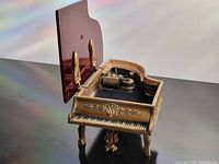 Grand piano music box with open Bakelite lid showing the music box mechanism inside.