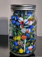 Glass jar filled with mixed color glass marbles, showing size and quantity approximately.
