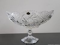 Clear glass cut crystal bowl with starburst and geometric cut patterns on an octagonal faceted pedestal base with original Yugoslavian sticker visible.