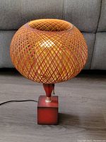 Lamp fully assembled and turned off, showing the woven fiberglass shade and wooden base.