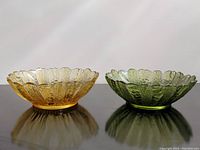 Both amber yellow and avocado green sunflower pattern glass bowls side by side