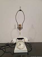 Front view of telephone-shaped mid-century clock lamp lighter, white textured base with black handset and clock face visible at front.