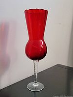 Full view of the vase showing the rich ruby red glass body, twisted clear glass stem, and round base.