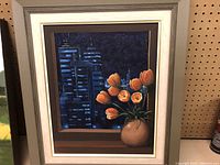 Framed oil painting showing orange tulips in a pot with a dark cityscape background at night