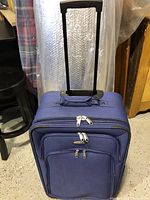 Navy blue softshell Samsonite suitcase with telescopic handle extended, showing front zippered compartments.