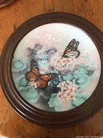 Collector plate with Monarch butterflies on flowers in round walnut wood frame