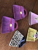 Five small purse-shaped ceramic plates displayed on wooden surface with different colors and decorative details.