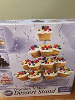 Box of Wilton Cupcakes 'N More Dessert Stand featuring cupcakes arranged on the stand.