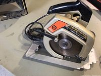Black & Decker 7 1/4 inch commercial circular saw resting on a workbench, showing blade, handle, and power cord.