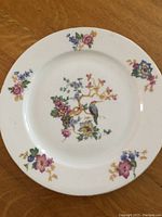 Plate with central floral and bird motif and smaller floral decorations at edges on white porcelain.