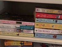 Shelf with 10 Fern Michaels paperback novels in various colors and titles visible on spine.