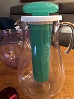 Clear plastic infuser pitcher with green infuser inside and green handle top