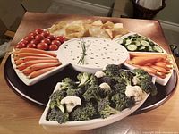 Top view of the Lazy Susan showcasing the black base with five white ceramic serving dishes arranged around a central round dish. Includes food props for scale and presentation.