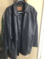 Full front view of navy blue leather mid-length jacket hanging on a hanger, showing collar, pockets, and button closure.