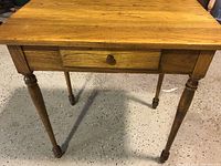 Front view of solid wood table with one drawer and turned legs
