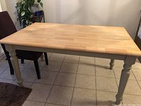 Front angle showing the table top with wood plank pattern and painted carved legs.