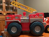 Close-up of red Tonka fire truck showing large black wheels and yellow ladder