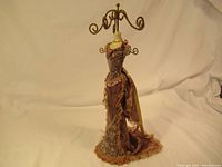 Full view of the decorative bust necklace stand dressed in fabric with twisted metal arms for hanging jewelry.