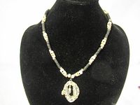 Full view of necklace displayed on black velvet form, showing bead stringing and geode pendant with dangling crystal.