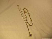 Two necklaces laid flat showing both items in full.