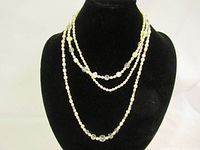 Three vintage pearl and bead necklaces displayed on black jewelry bust, showing layered length and bead styles.