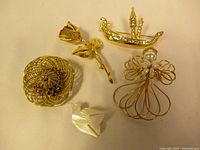 Lot of five brooches including wire hat, gold leaf, boat, wire angel, and mother-of-pearl dove.
