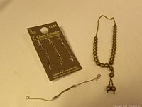 Three 2-inch metal chain extenders on retail card labeled '$2.88', alongside a vintage-style metallic beaded necklace with toggle clasp.