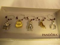 Full set of 5 Pandora charms in Pandora branded box showing all charms on wire rings with purple beads.