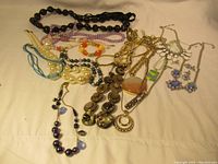Top view of assorted necklaces and jewelry spread out showing a variety of materials and colors including beads, chains, and pendants.