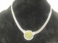 Necklace displayed on black jewelry bust showing silver-tone chain with round Roman coin pendant.