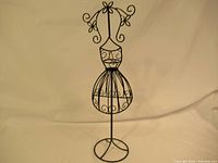 Full view of the metal necklace and jewelry stand shaped like a female mannequin with decorative wirework.