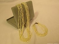 Full view of the multi-strand pearl necklace draped over a grey display stand showing off the pearls and length.