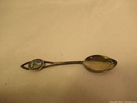 Full view of the sterling silver spoon showing overall shape, attached token, and signs of wear.