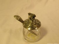 Full view of jar with pewter lid and spoon inserted showing decorative details.
