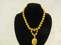 Full view of the vintage yellow button flower necklace on a black display bust, showing the beaded design and pendant.