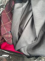 Close up of assorted textile fabrics in various colors including reddish-brown with a patterned print, gray, and bright pink knit fabric.