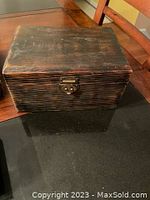 Dark brown wooden jewelry box with latch on front, showing wood grain and minor wear
