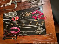 Various metal-tone, pearl and bead necklaces laid out on dark surface