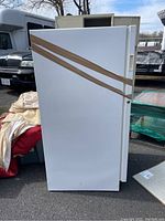 Side view of the white upright freezer wrapped with brown packing tape.