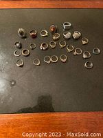24 assorted fashion rings arranged on black surface