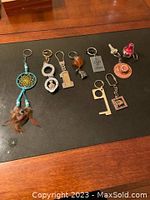 Photo of 10 assorted key chains with various shapes including dreamcatcher, handcuff, number 1, glass orb, LOVE tag, miniature key, Santa hat with sheep, sombrero, number 9 tool, and square frame.