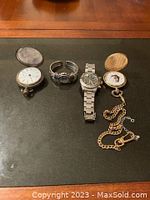 Two sterling and gold-tone pocket watches, stainless steel chronograph and silver-tone cuff watch displayed on black mat